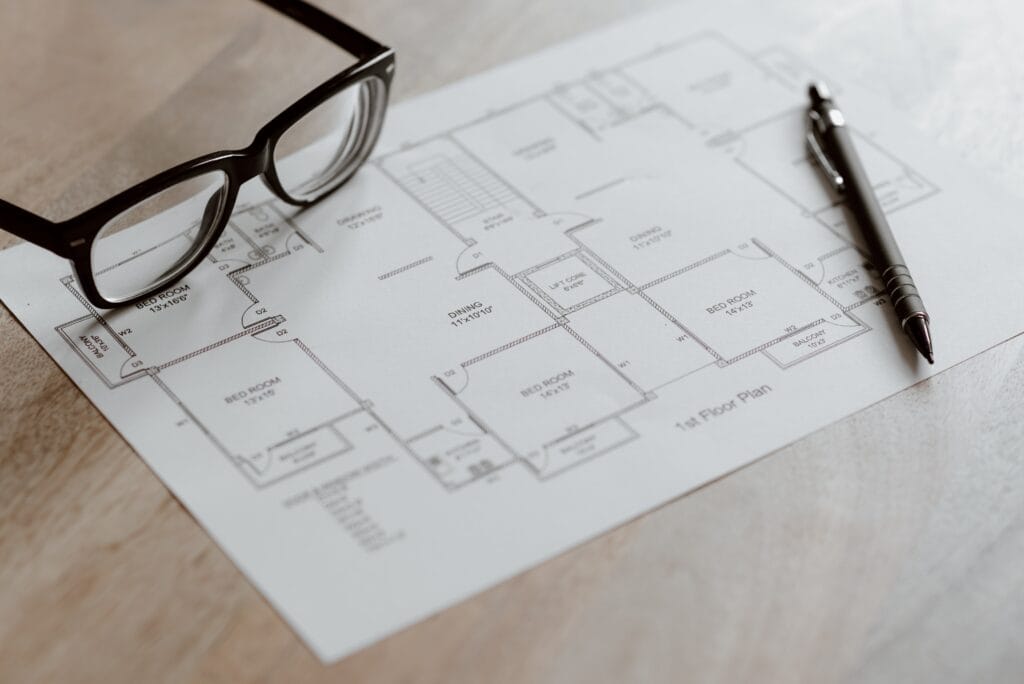 Architektenplan mit Brille und Kugelschreiber auf Holztisch