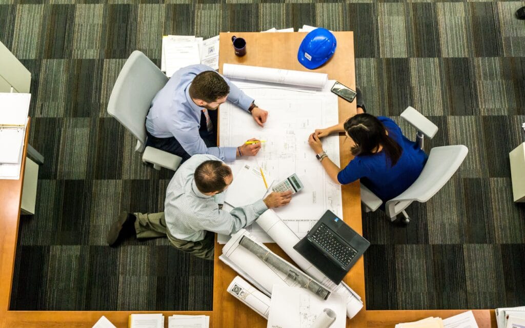 Architekten sitzen über Plänen an einem Tisch, Aufnahme von oben