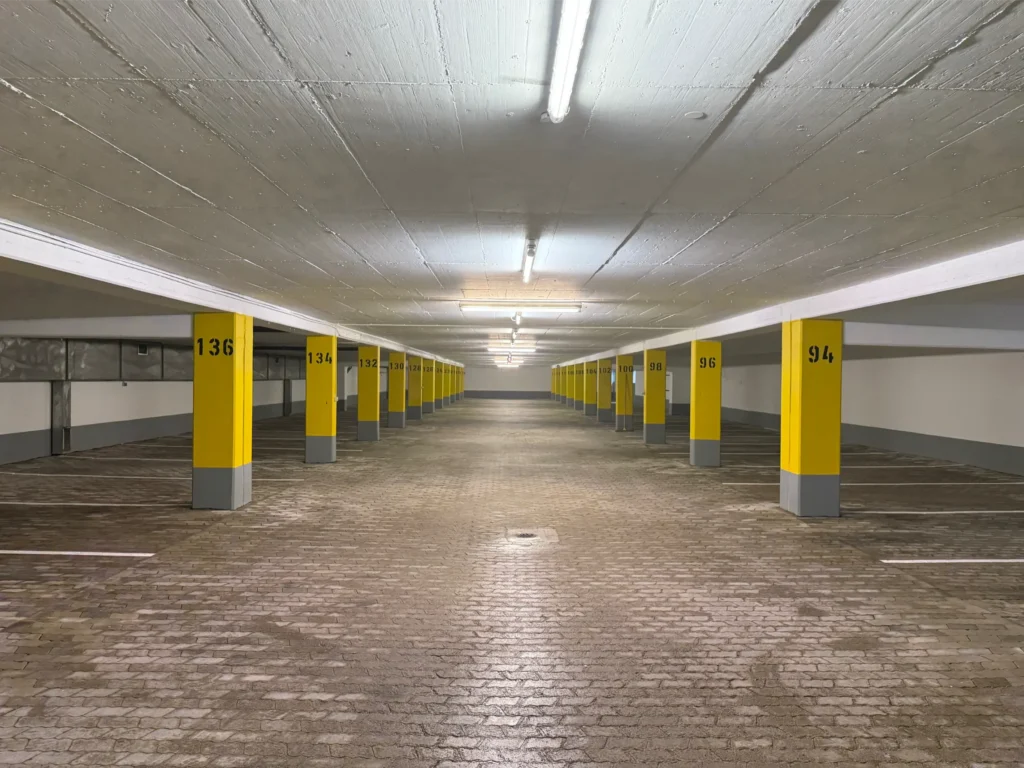 Sanierte Tiefgarage mit nummerierten Stellplätzen und frisch gestrichenen Stützen in München.