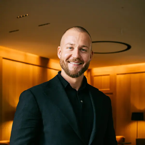 Lucas Peter Ellmer, Geschäftsführer der LPE Immobilien Management GmbH in München, im Porträt – lächelnd in moderner Lobby mit Holzverkleidung im Hintergrund.