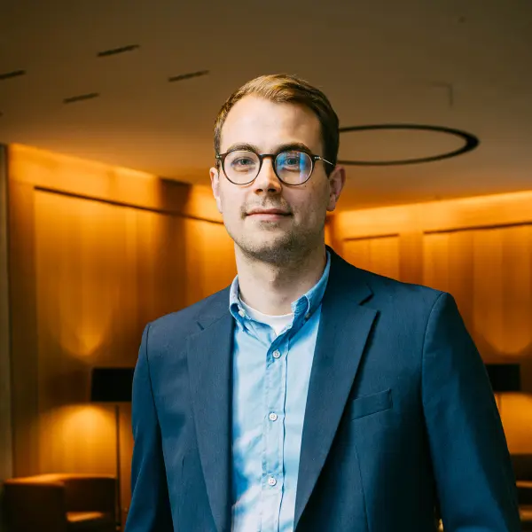 Marius May, Head of WEG Property Management bei LPE Immobilien Management GmbH in München, im Porträt mit Anzug und Brille in moderner Büro-Lounge.