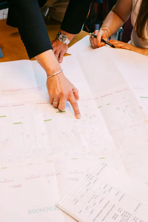 „Hand zeigt auf Grundrissplan – Besprechung der technischen Details am Tisch